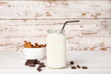 Mason jar of tasty milkshake on white table