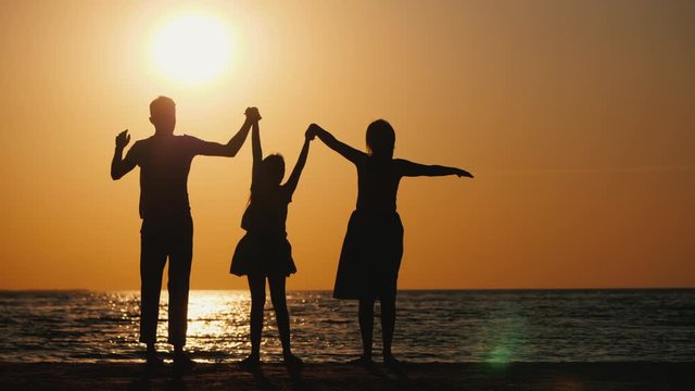 A family with a child raise their hands at sunset. Friendly healthy sei a concept