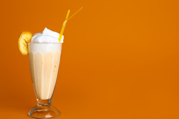Glass of tasty milkshake on color background