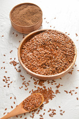 Bowls with flax seeds, powder and spoon on white background