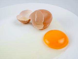 Broken eggs on a plate white background. reddish yellow