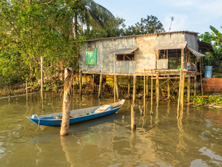 Fototapeta na wymiar Stilt cabin and a boat in the Mekong River Delta - Can Tho, Vietnam