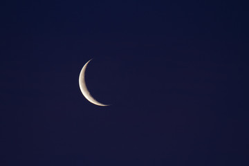 Waning crescent moon in dark blue sky