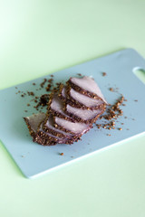 Sliced boiled pork on a blue cutting board on a mint background. An ingredient for a ketogenic diet. Low carbohydrate, high fat.