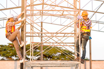 Technicians in safety clothing are climbing scaffolding. Friends go up and check the strength of the metal roof part of the building.