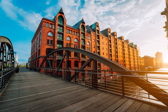 Arch bridge over canals in the Speicherstadt of Hamburg. Warm evening sun light on red brick building