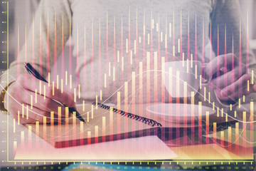 Forex chart hologram on hand taking notes background. Concept of analysis. Double exposure