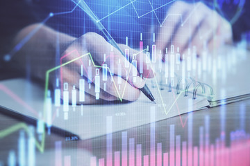 Forex graph on hand taking notes background. Concept of research. Double exposure