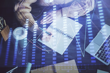 Forex graph on hand taking notes background. Concept of research. Double exposure