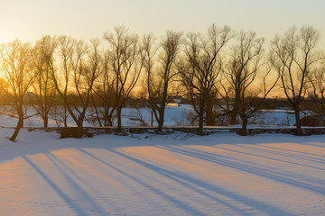 Evening winter landscape with thawed areas, ravines and trees