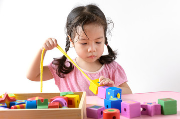 Little curly asian girl enjoy playing with wooden toy blocks isolated on white background. Education and learning Concept.