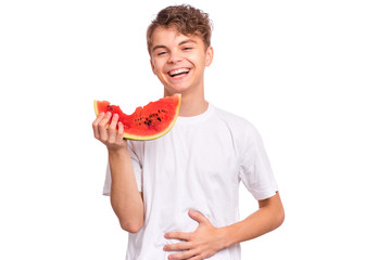 Portrait of teen boy eating ripe juicy watermelon and smiling. Cute caucasian young teenager with slice healthy watermelon. Funny happy child wearing white t-shirt, isolated on white background.