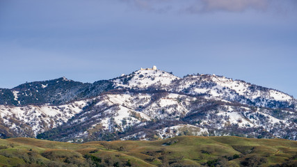 Fototapeta na wymiar View towards the top of Mt Hamilton on a clear winter day, snow covering the summit and the surrounding hills; San Jose, San Francisco bay area, California