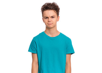 Upset handsome caucasian Teen Boy in blue t-shirt, isolated on white background. Teenager looking at camera. Unhappy child - close-up portrait.