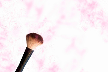 Makeup brush on a white background with a splash of pink powder.