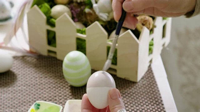 Close-up shot of caucasian woman painting Easter eggs at home. 4K