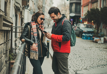Young couple looking a mobile phone, talking and laughing about it