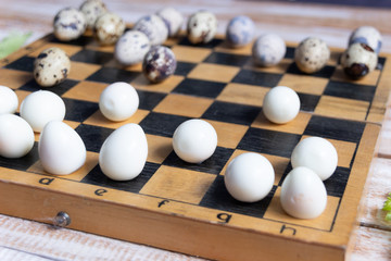 Easter chess match with fresh and boiled quail eggs on wooden background close up