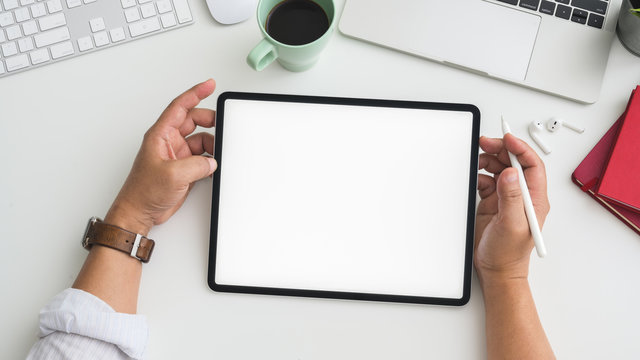 Overhead shot of Businessman working on tablet in workspace with computer, laptop and other office supplies - Powered by Adobe