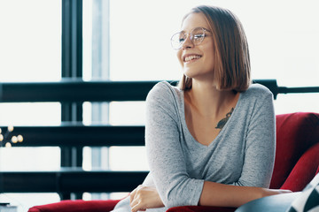 Attractive girl sitting in a red cozy chair