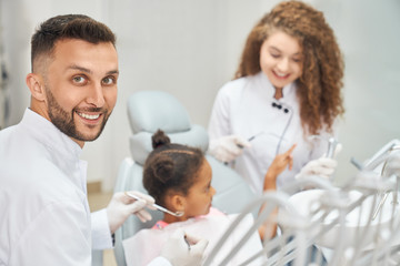 Fototapeta premium Afro girl in dental chair with dentist and assistant around