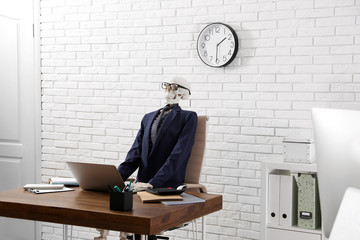Human skeleton in suit using laptop at table in office
