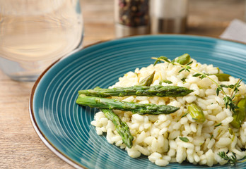 Delicious risotto with asparagus served on wooden table, closeup