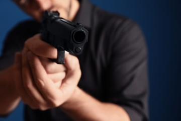 Man holding gun on dark blue background, focus on barrel