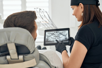 Female dentist showing x-ray picture of teeth to patient