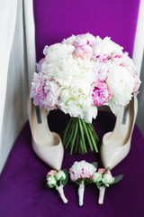 Pair of elegant and stylish bridal shoes with a bouquet with roses and other flowers