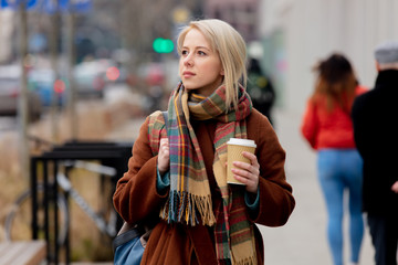 Obraz premium Beautiful blonde woman with cup of coffee on city street