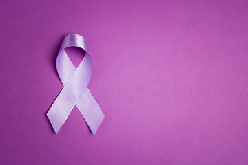 Purple awareness ribbon on a purple backgroundwith copy space. - Powered by Adobe