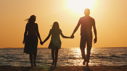 Family with a child goes to the sea at sunset © StockMediaSeller