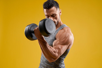 Handsome bodybuilder working out with dumbbell - obrazy, fototapety, plakaty