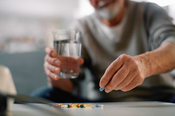 Close up of old man taking pills. Senior man drinking medicine. 