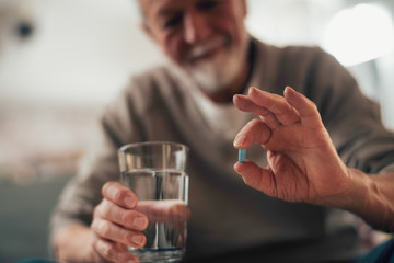 Close up of old man taking pills. Senior man drinking medicine. 