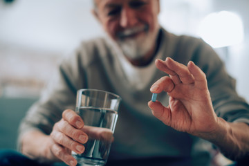 Close up of old man taking pills. Senior man drinking medicine. 