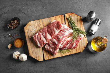 Raw ribs with herbs and spices on grey table, flat lay