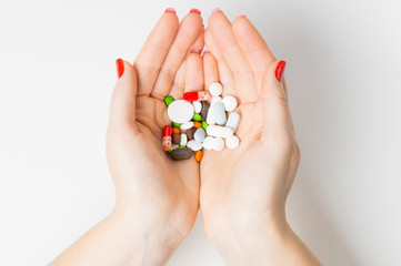 medicines and tablets in women's hands top view on white background, concept of medicine and health care