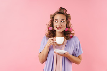 Image of pleased thinking woman looking aside while drinking coffee