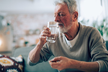 Old man taking pills. Close up of senior man drinking medicine. 