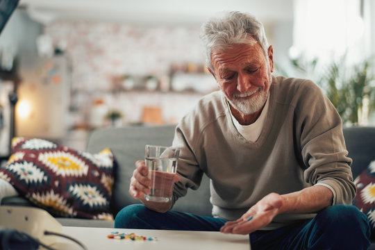 Old man taking pills. Senior drinking medicine. 