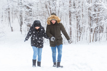 Young couple walking in a snowy park. Winter season.