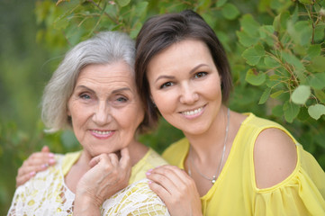 Smiling senior woman with adult daughter in autumnal park