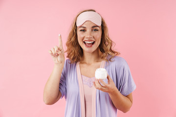 Image of caucasian cheerful woman smiling while applying face cream