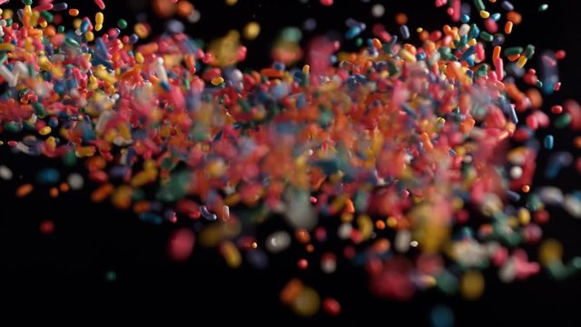 Camera follows rainbow chocolate sprinkles frying in the air. Slow Motion. 