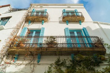 Cadaqués, Catalonia / Spain - November 30th, 2019: Old traditional white facade with turquoise...