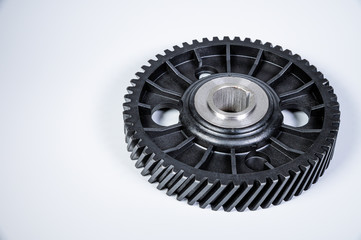 Black polymer gear camshaft with metal base. New spare part for an internal combustion engine on a gray background