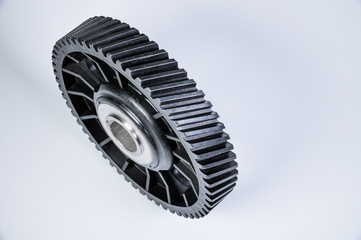 Black polymer gear camshaft with metal base. New spare part for an internal combustion engine on a gray background