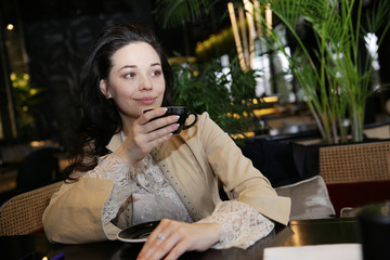 young beautiful woman drinks coffee or tea in cafe in soft blur background